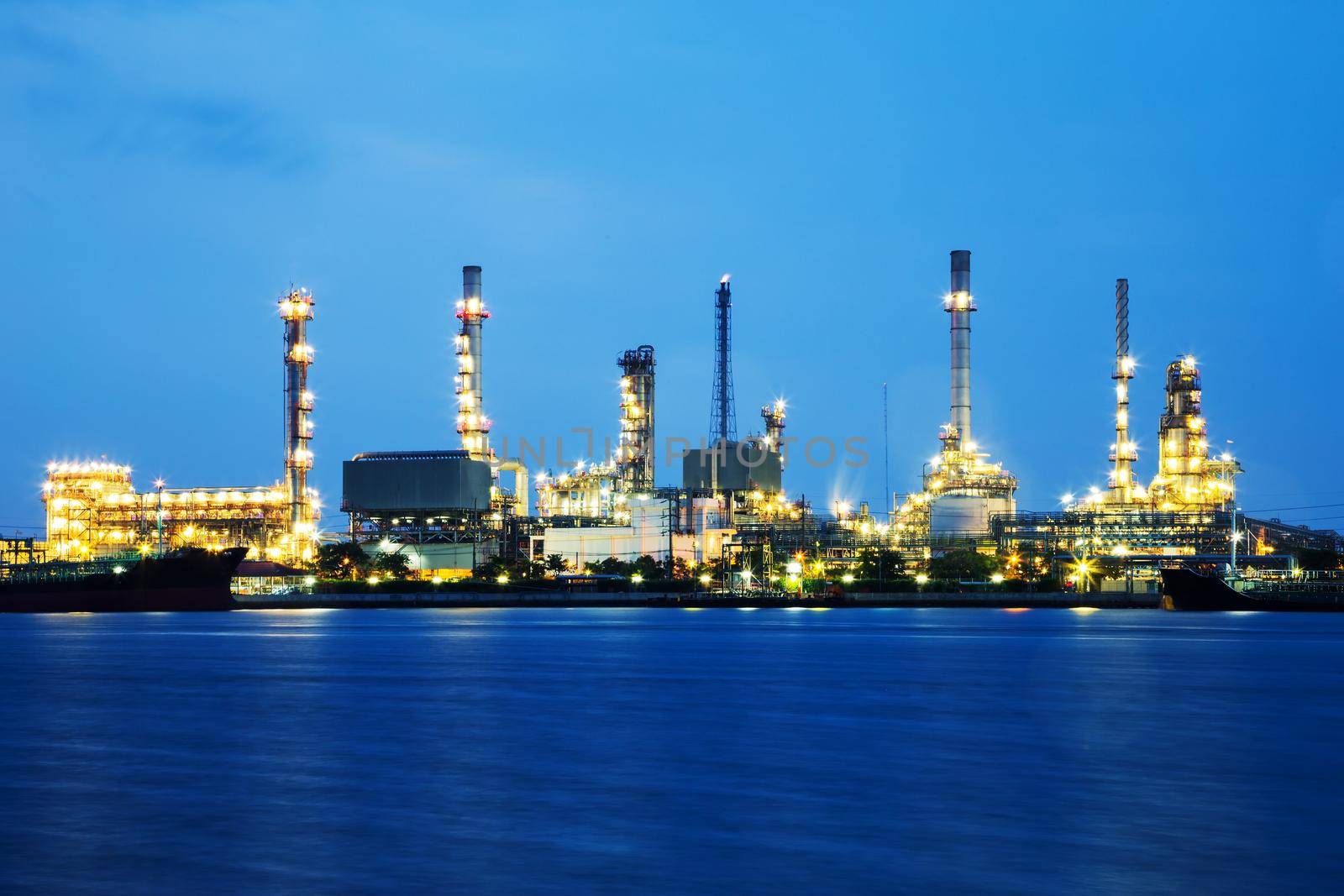 Oil refinery industry with tube and oil tank along twilight sky