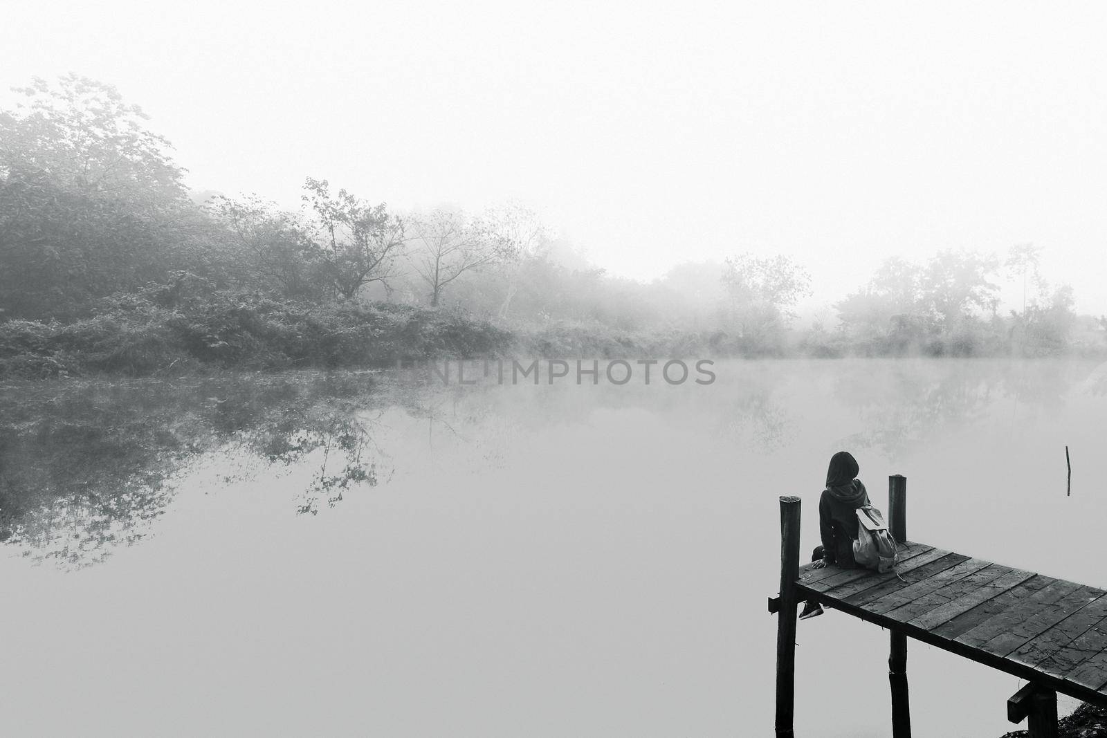 Young women sitting on a wooden bridge. Black and white picture