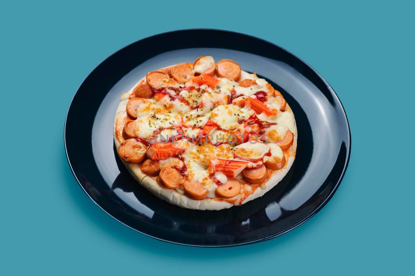 Sausage and Crab Stick Pizza in a ceramic plate isolated on pastel colors background.