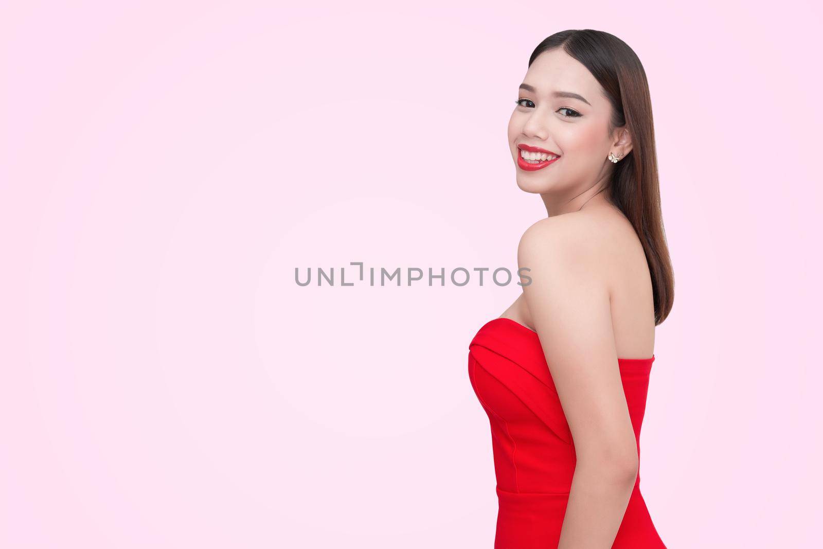 Beautiful sexy young woman in a red dress on a pink background