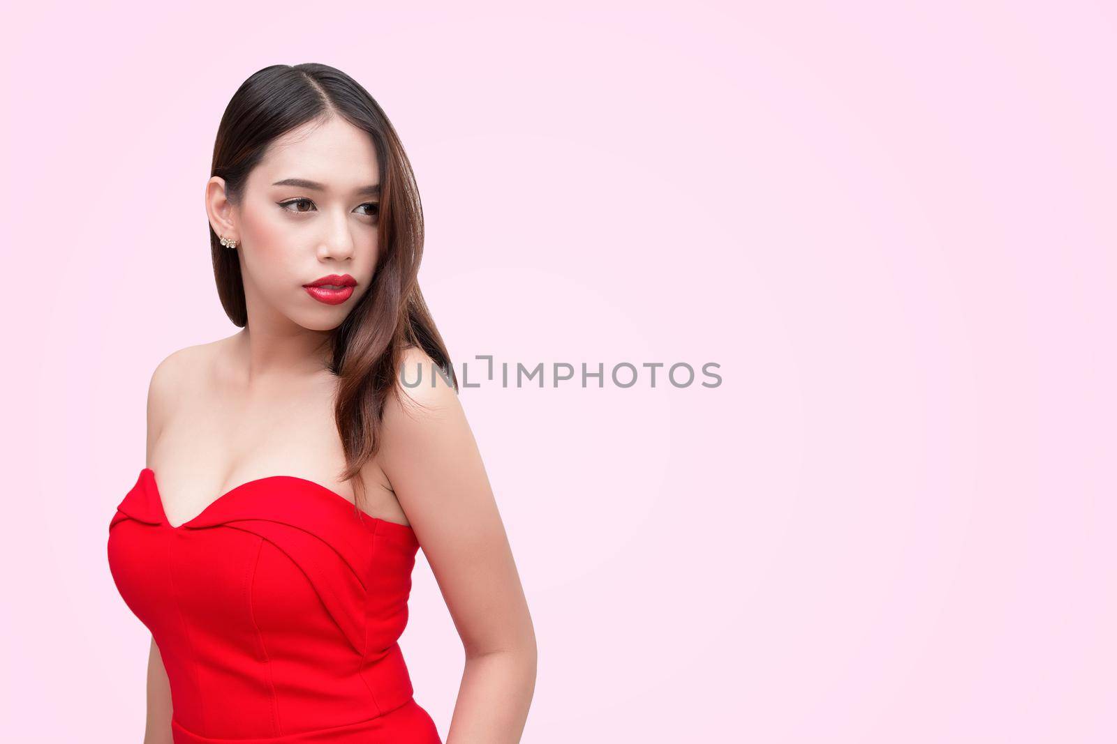 Beautiful sexy young woman in a red dress on a pink background