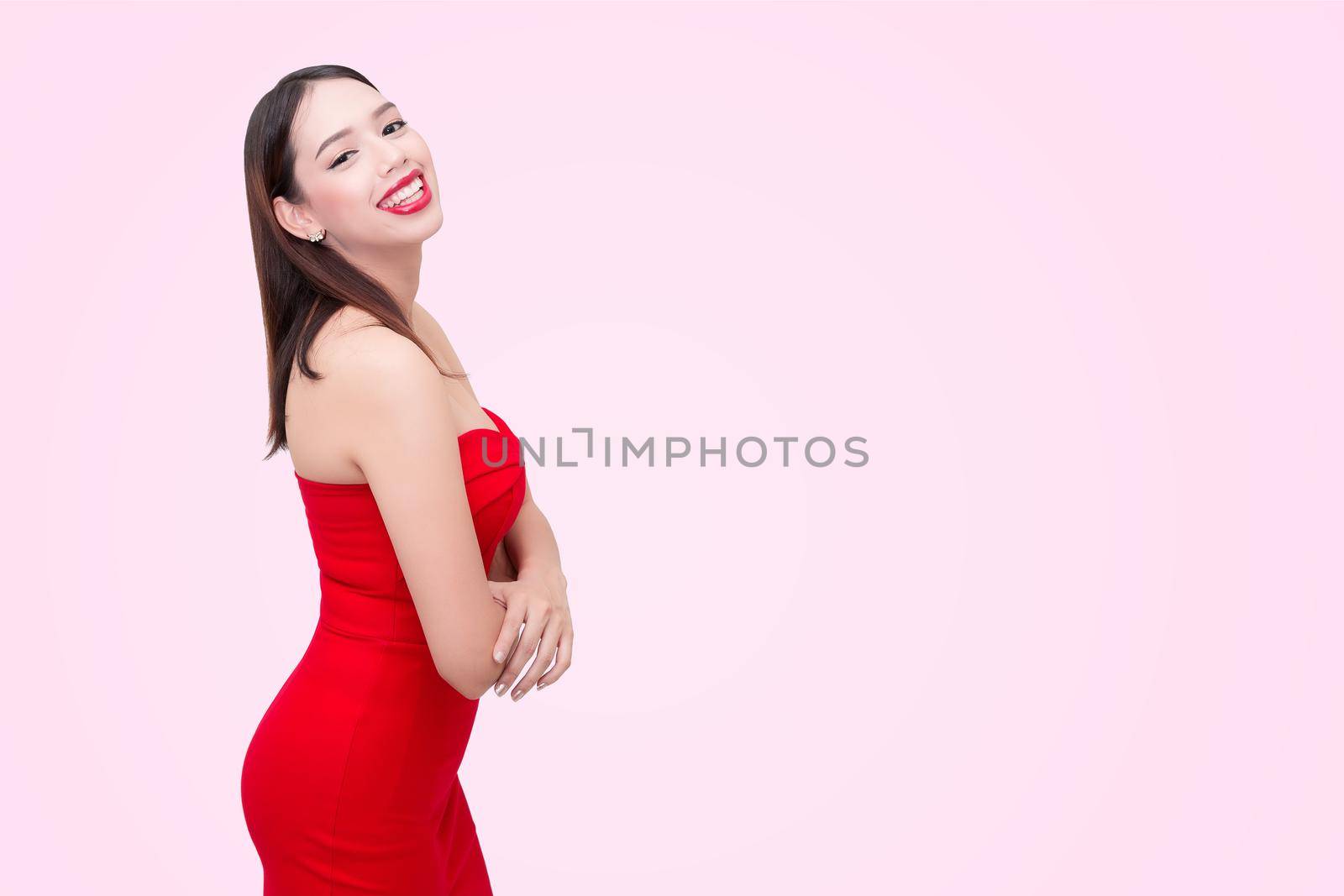 Beautiful sexy young woman in a red dress on a pink background