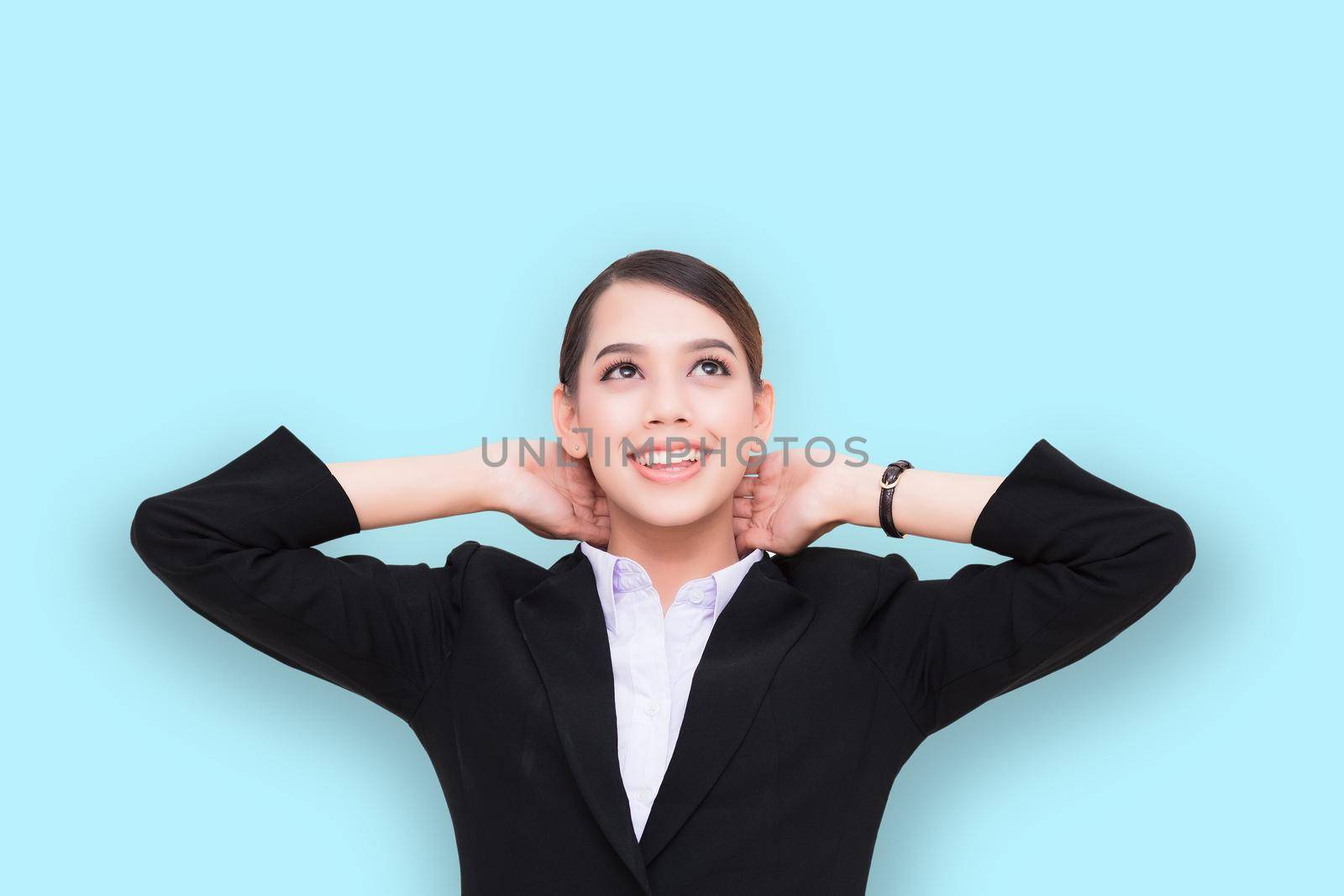 Businesswoman with beaming smile is relaxing, hands behind head, dreaming and enjoying