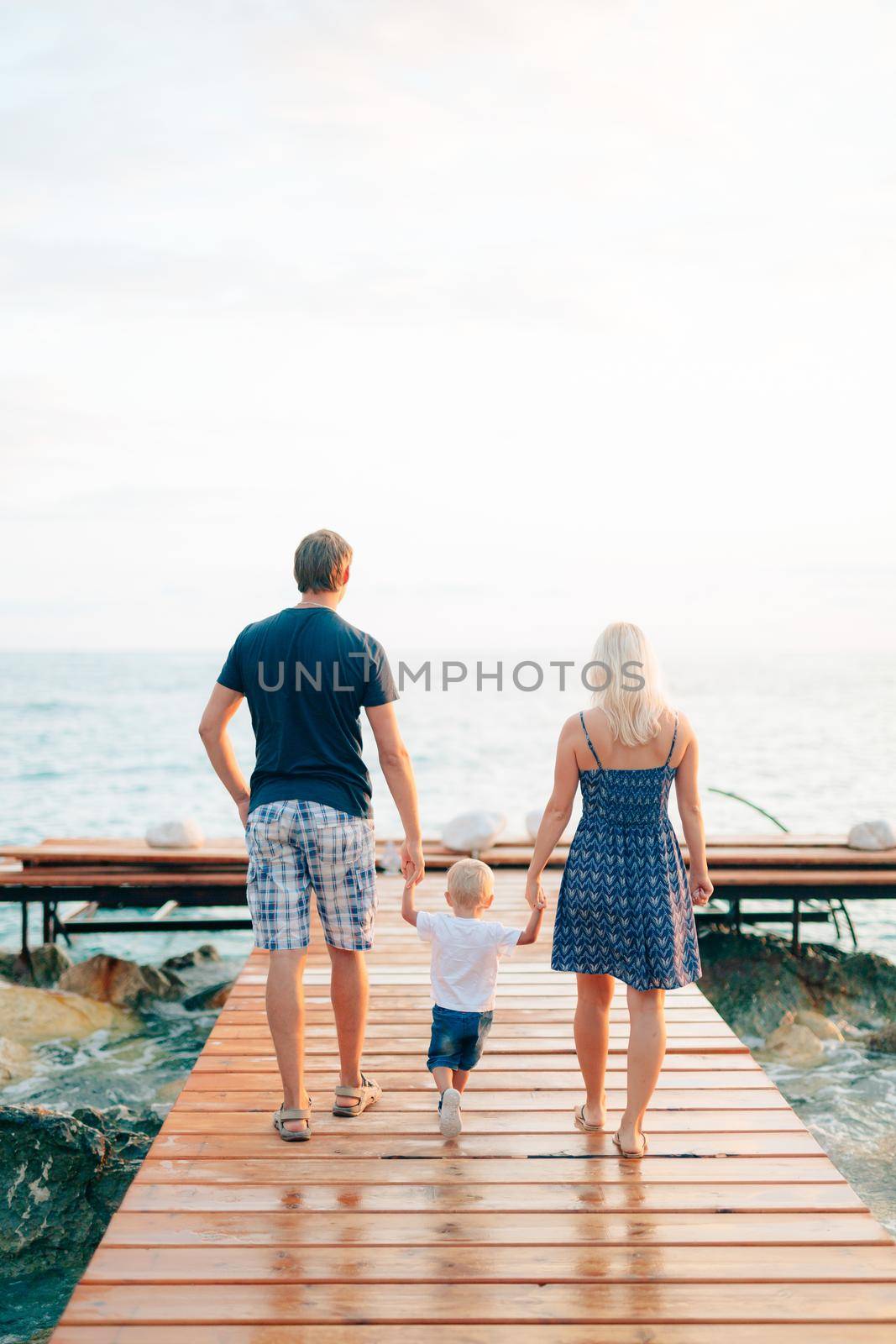 Parents with a daughter at the sea. Dad and mom are holding the by Nadtochiy
