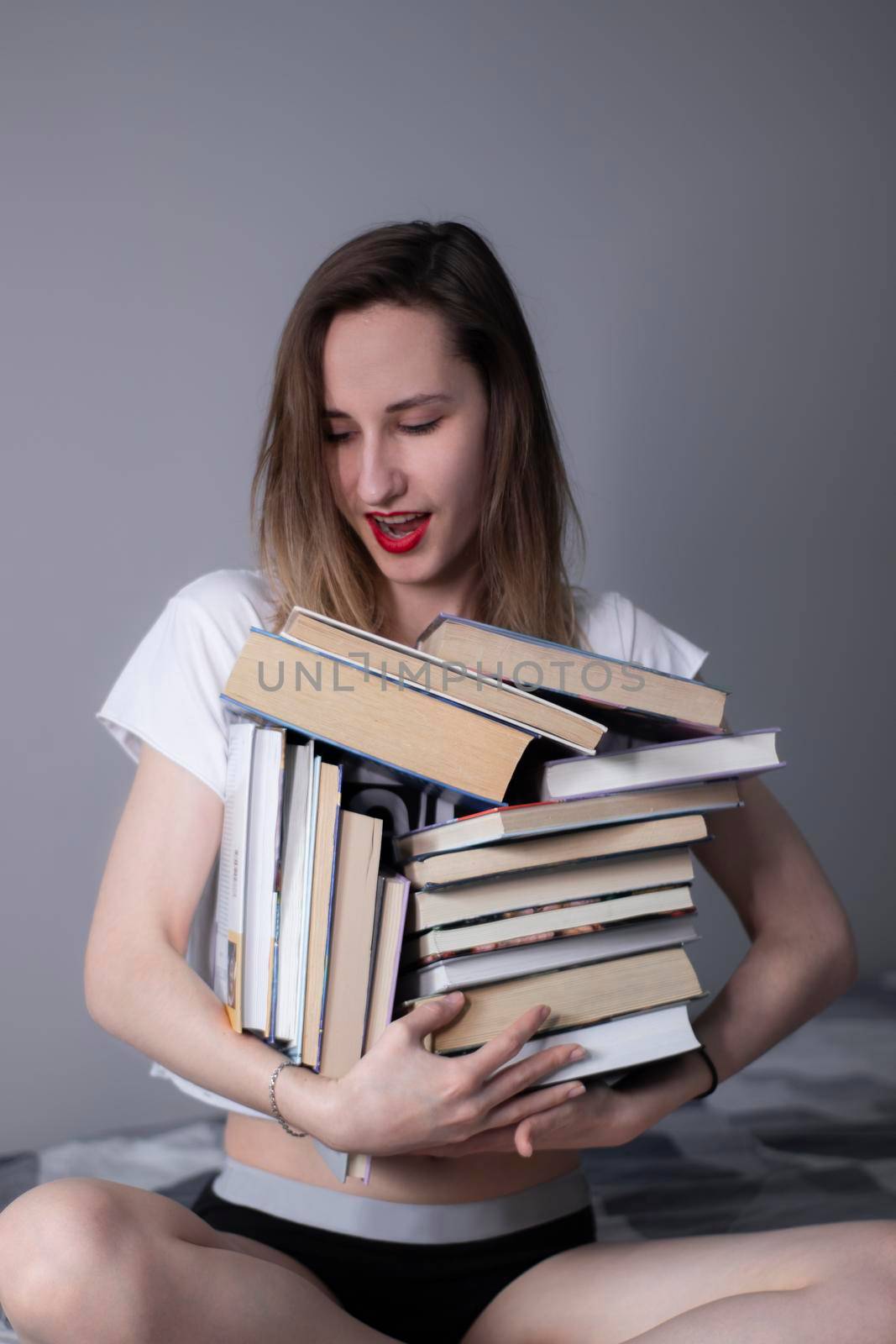 happy beautiful slim girl holds a lot of different books in her hands. Homeschooling. Reading is helpful