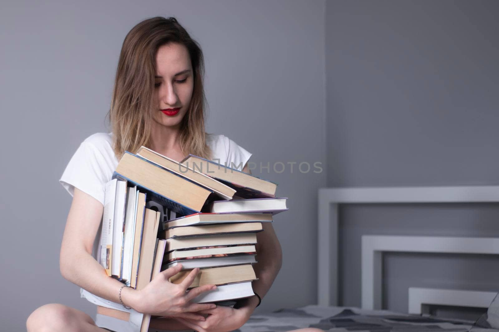happy beautiful slim girl holds a lot of different books in her hands. Homeschooling. Studying in quarantine. Reading is helpful - horizontal photo