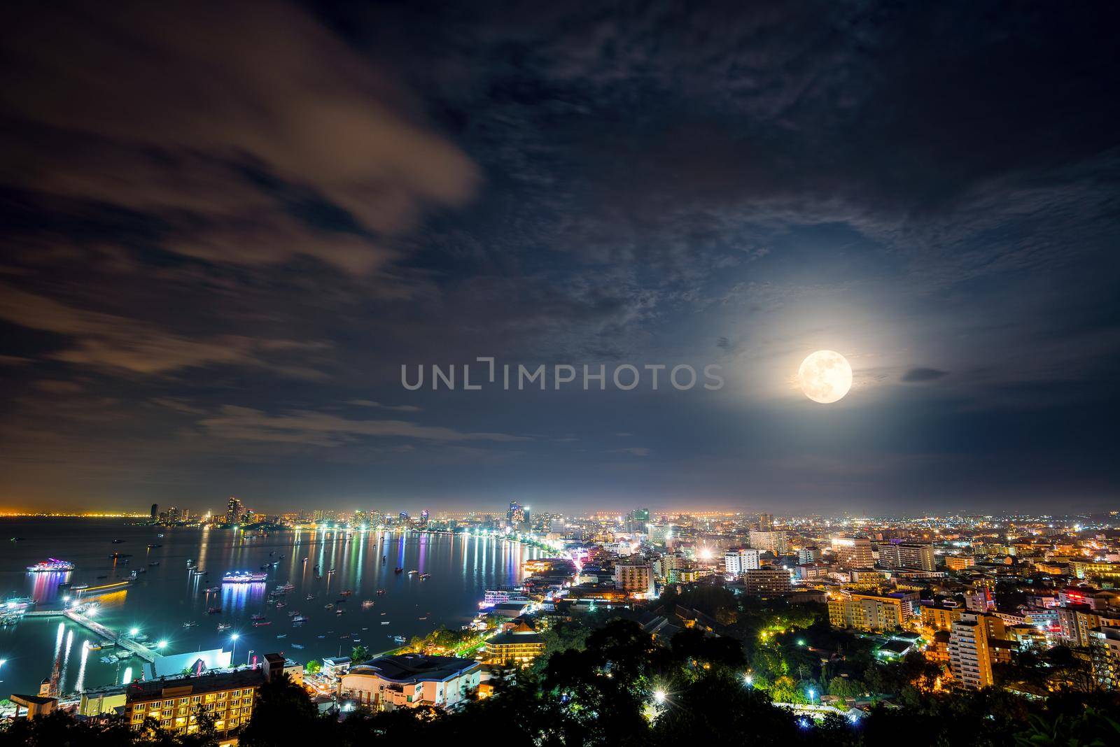 High view on viewpoint full moon above cityscape with colorful light at the sea beach of Pattaya Bay, beautiful landscape Pattaya City at night scene landmark in Chonburi, Travel Asia to Thailand