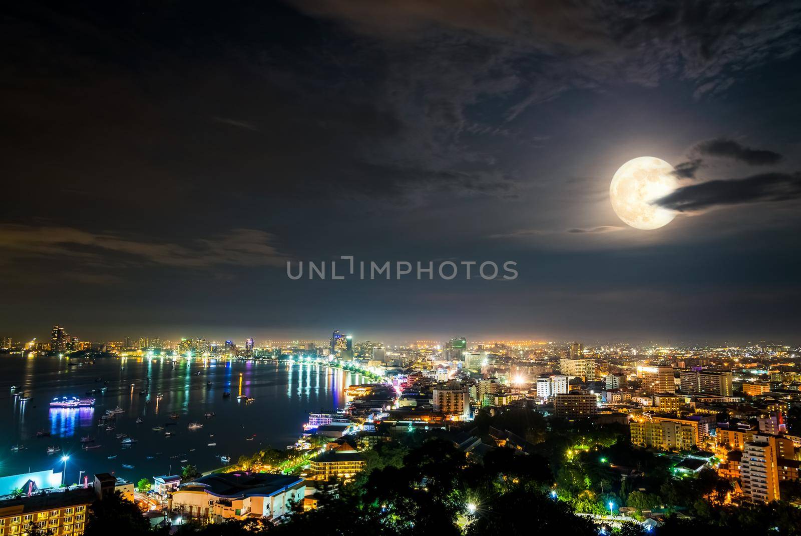 High view on viewpoint full moon above cityscape with colorful light at the sea beach of Pattaya Bay, beautiful landscape Pattaya City at night scene landmark in Chonburi, Travel Asia to Thailand