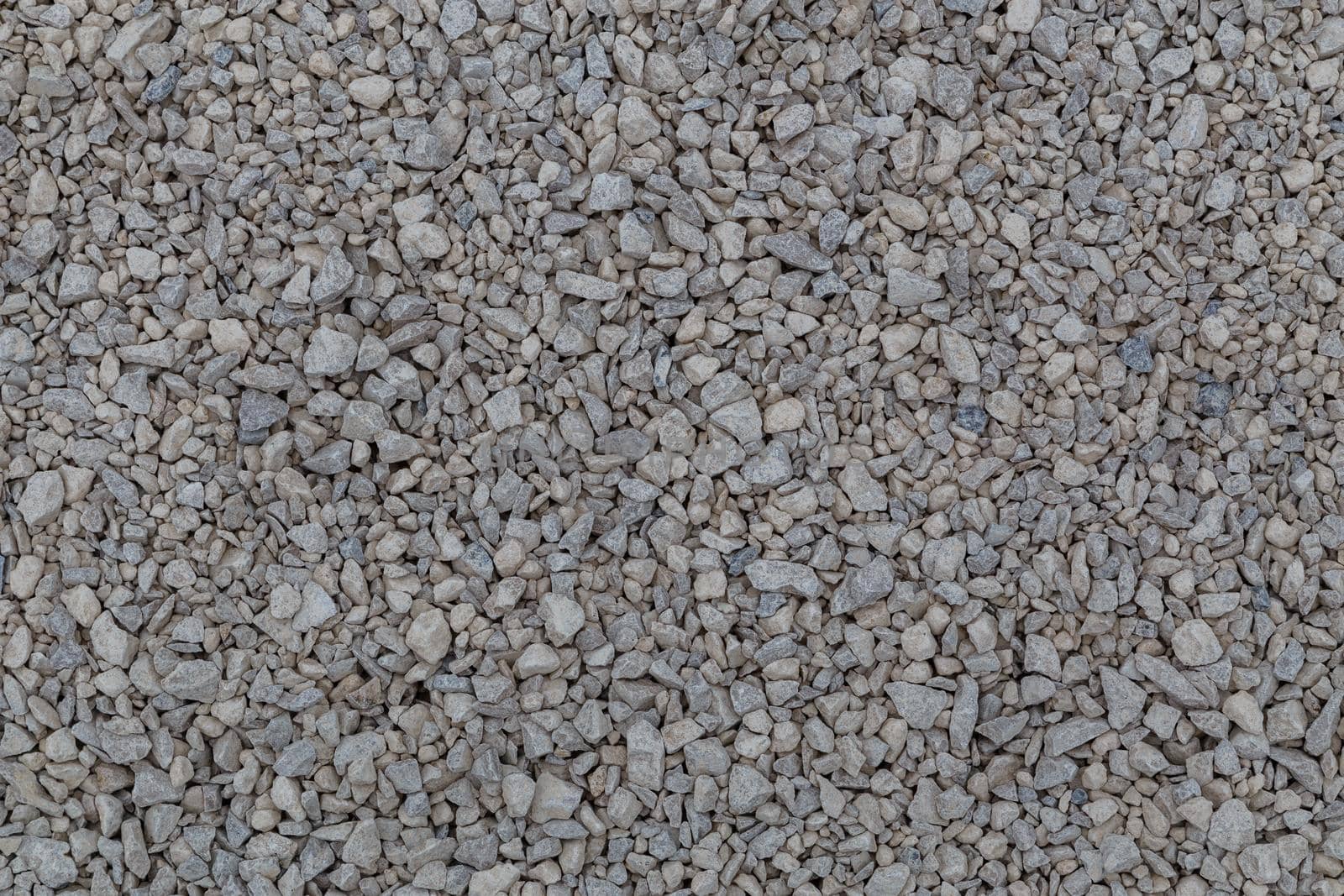 Dry white limestone ballast flat full frame background. Small gray dusty broken macadam stones texture. Viiew from above.