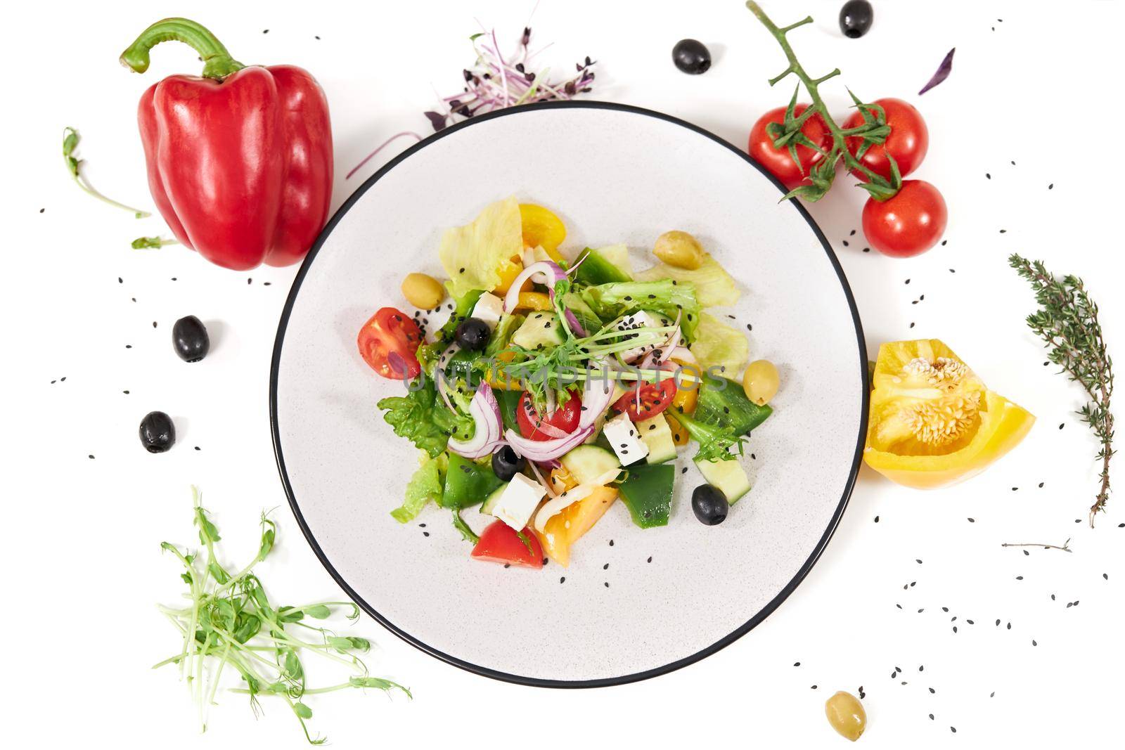 Top view of large modern plate with delicious vegetables salad on white background. Concept of beautiful composition with different colours greens and peppers. 