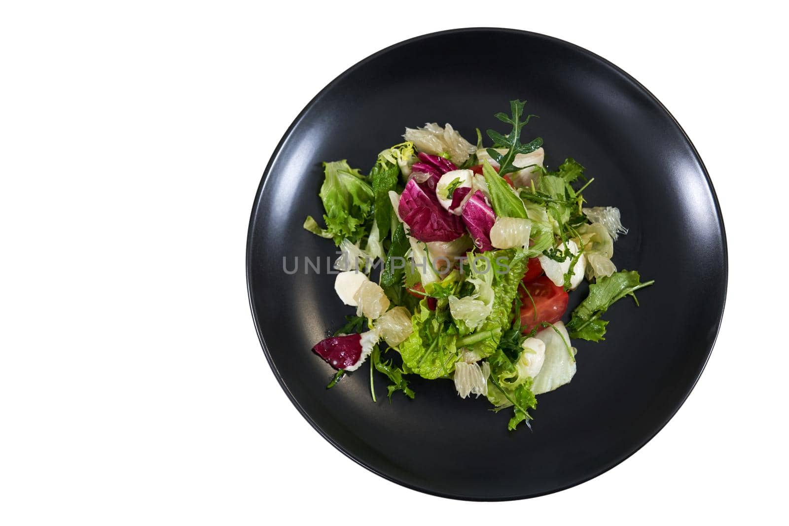 Top view of modern black plate with appetizing fresh salad with green leaf, arugula,tomatoes on white background. Concept of salad with many vitamins for maintain a healthy fitness.