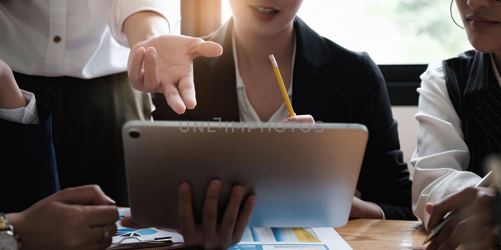 A group of businesswomen and accountants examine data documents on a digital tablet in preparation for an investigation into a corruption case by itchaznong