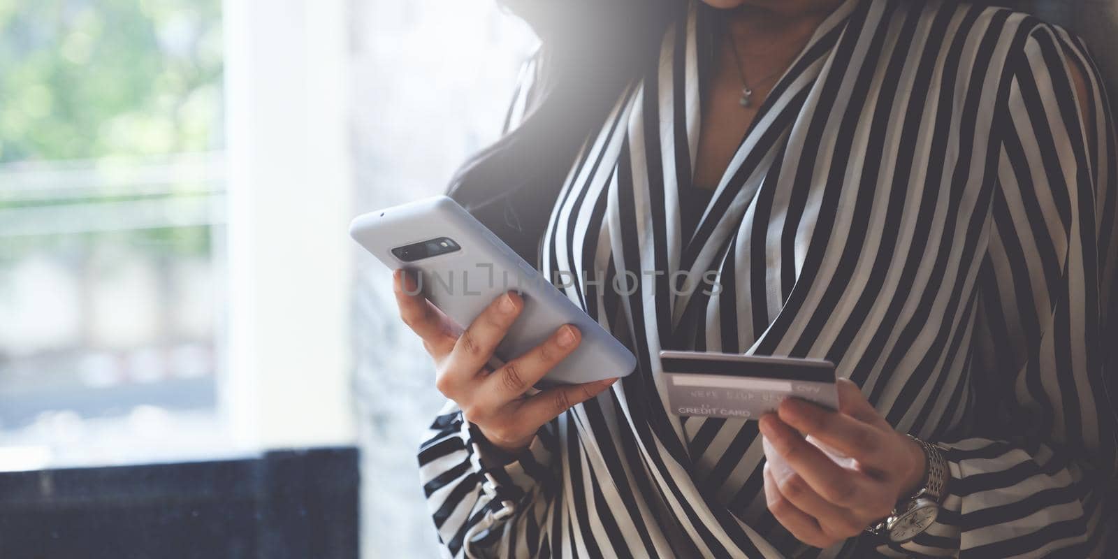 Woman enjoys using an online shopping program and checking her credit card for a payment number.