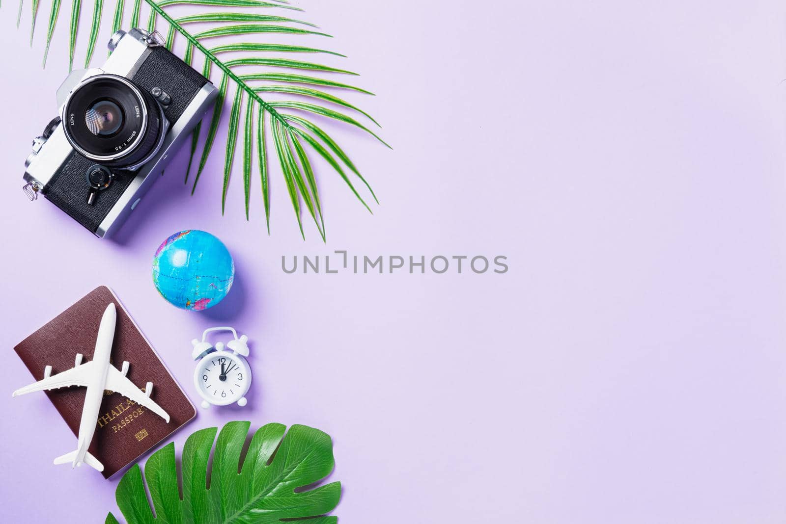 Top view flat lay mockup of retro camera films, airplane, passport, world and traveler accessories isolated on a purple background with copy space, Business trip, and vacation summer travel concept