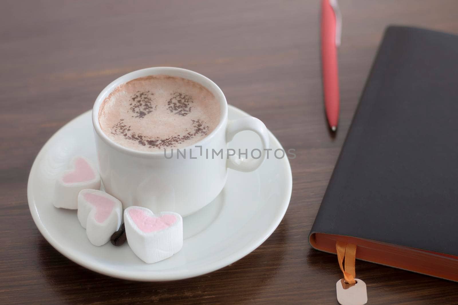 Coffee with milk or hot chocolate in a white cup and sweet in the form of hearts.