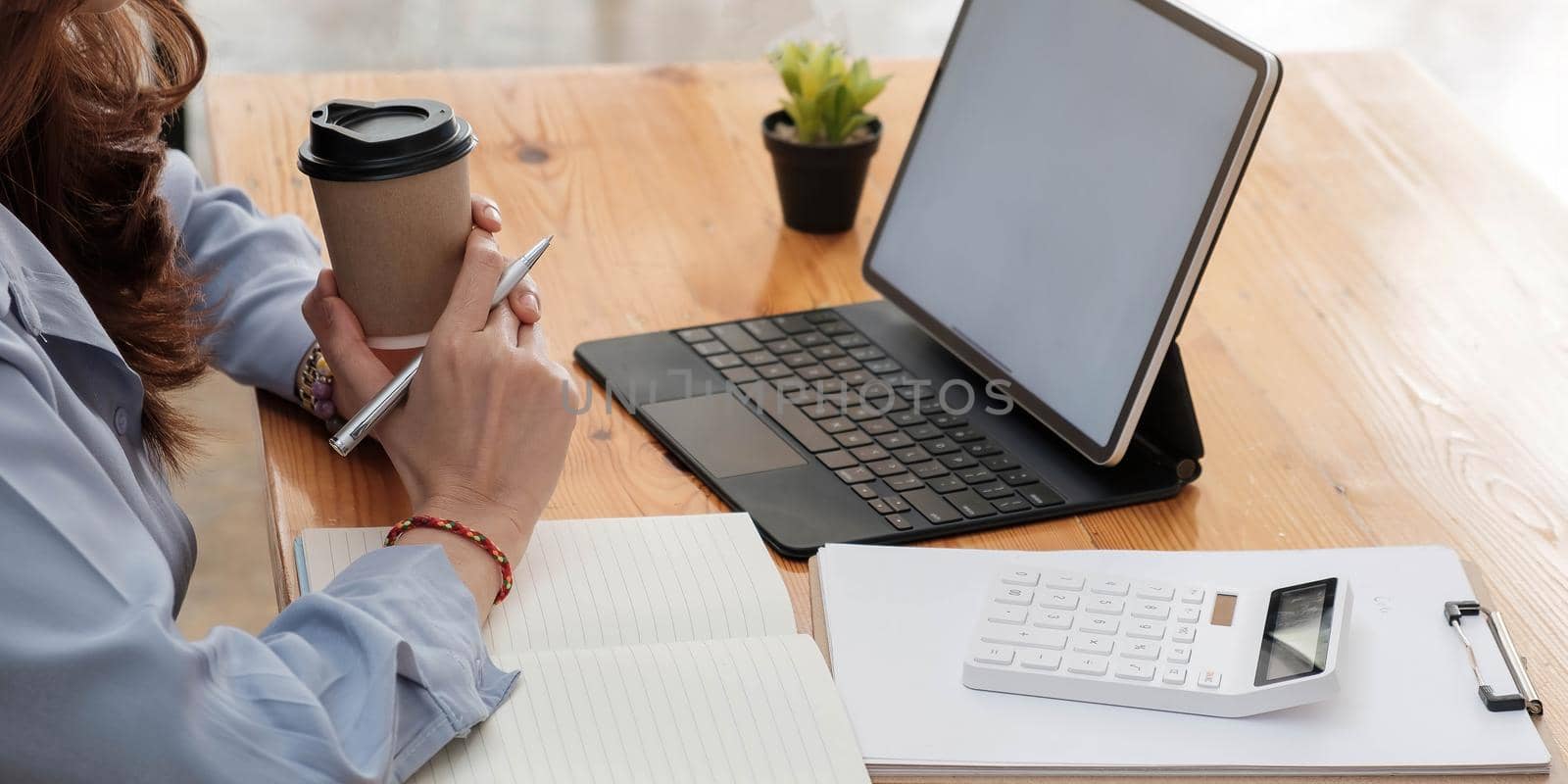 Portrait of businesswoman on workplace with laptop computer and notepad..