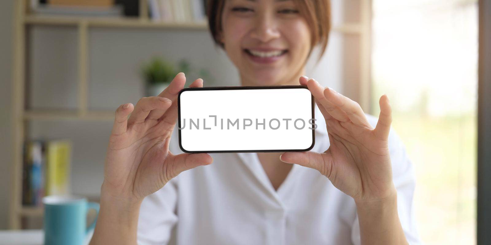 Mockup image of a beautiful woman hold a mobile phone with blank white screen by wichayada