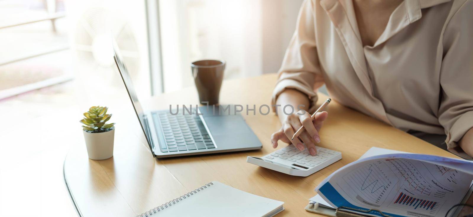 Business woman working in finance and accounting Analyze financial budget with calculator and laptop computer in the office.