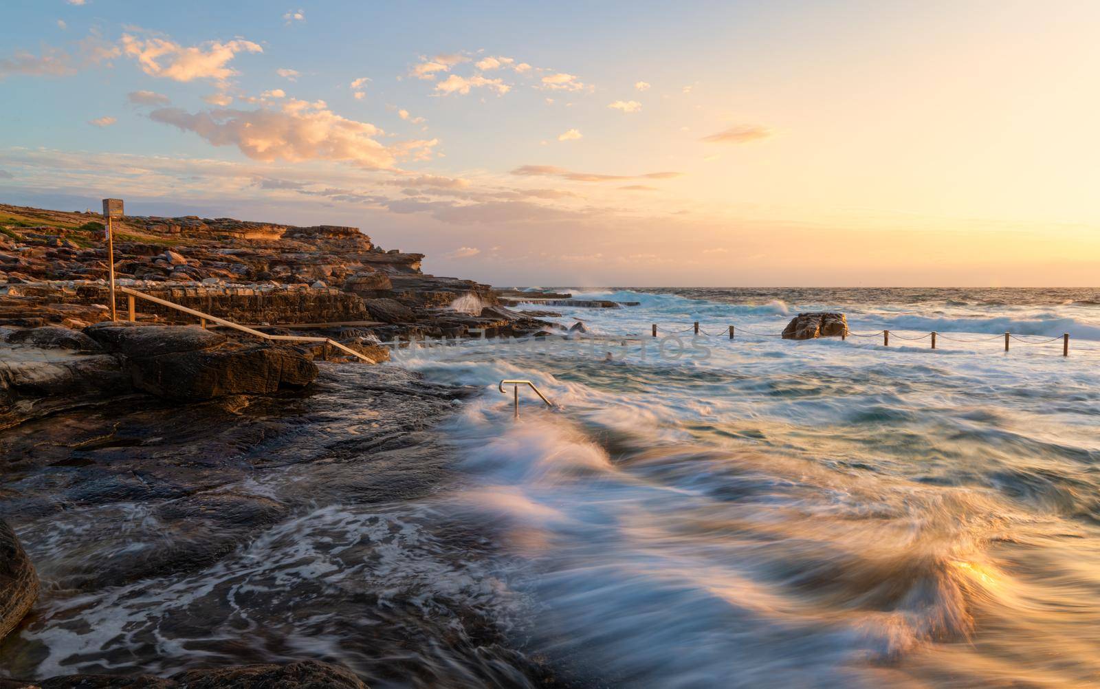 Early morning swimmers attempt to swim laps in turbulent ocean rock pool by lovleah