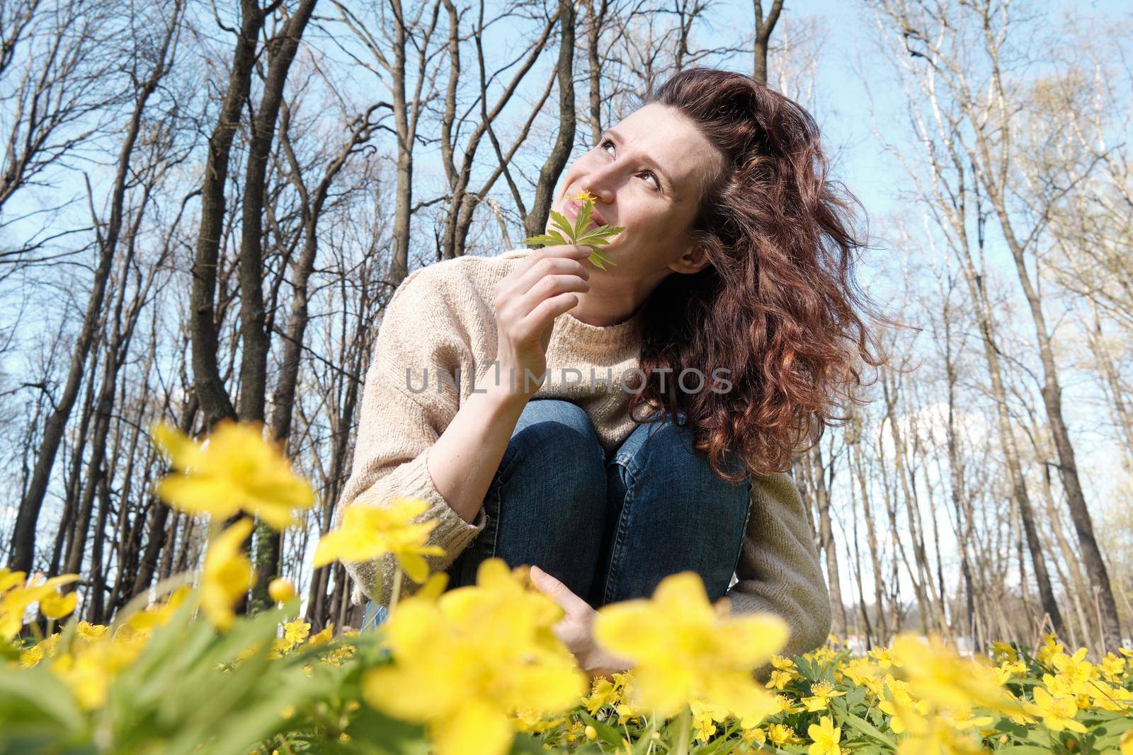 Woman enjoying smell of spring flowers. Smiling woman among spring flowers.