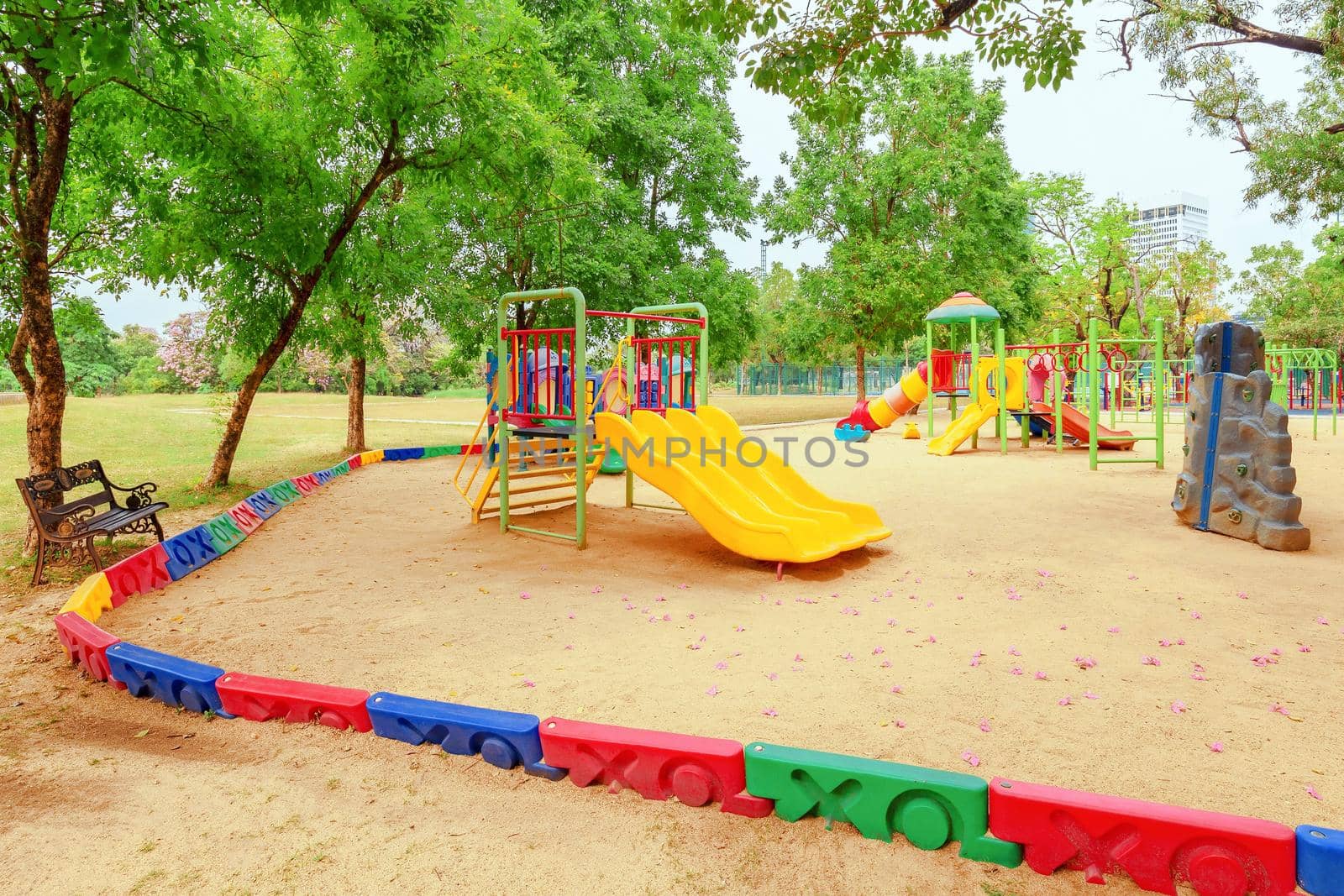 Colorful children playground activities in public park surrounded by green trees