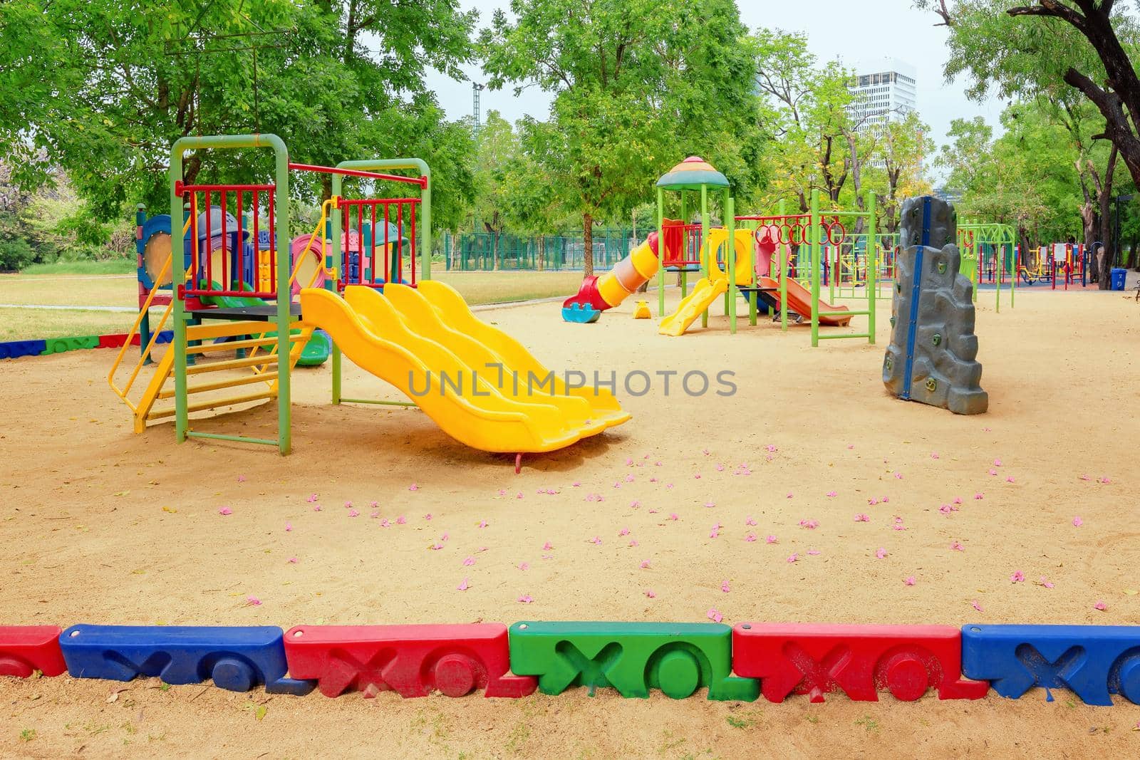 Colorful children playground activities in public park surrounded by green trees