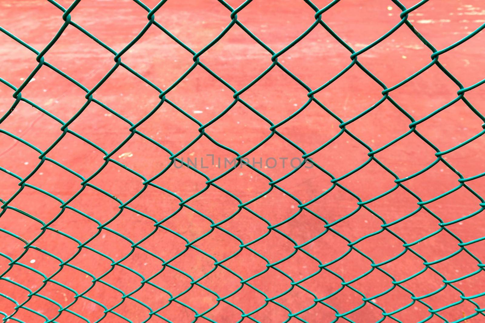 Close up steel wire mesh fence. orange color of the ground is the background.