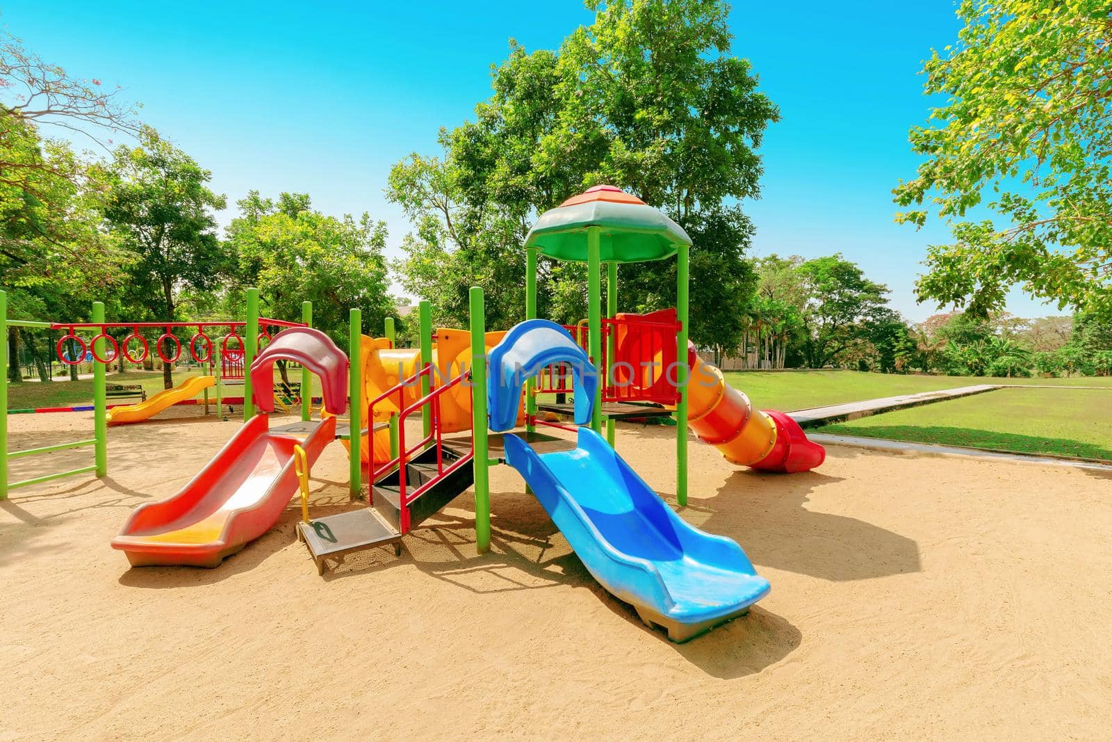 Colorful children playground activities in public park surrounded by green trees