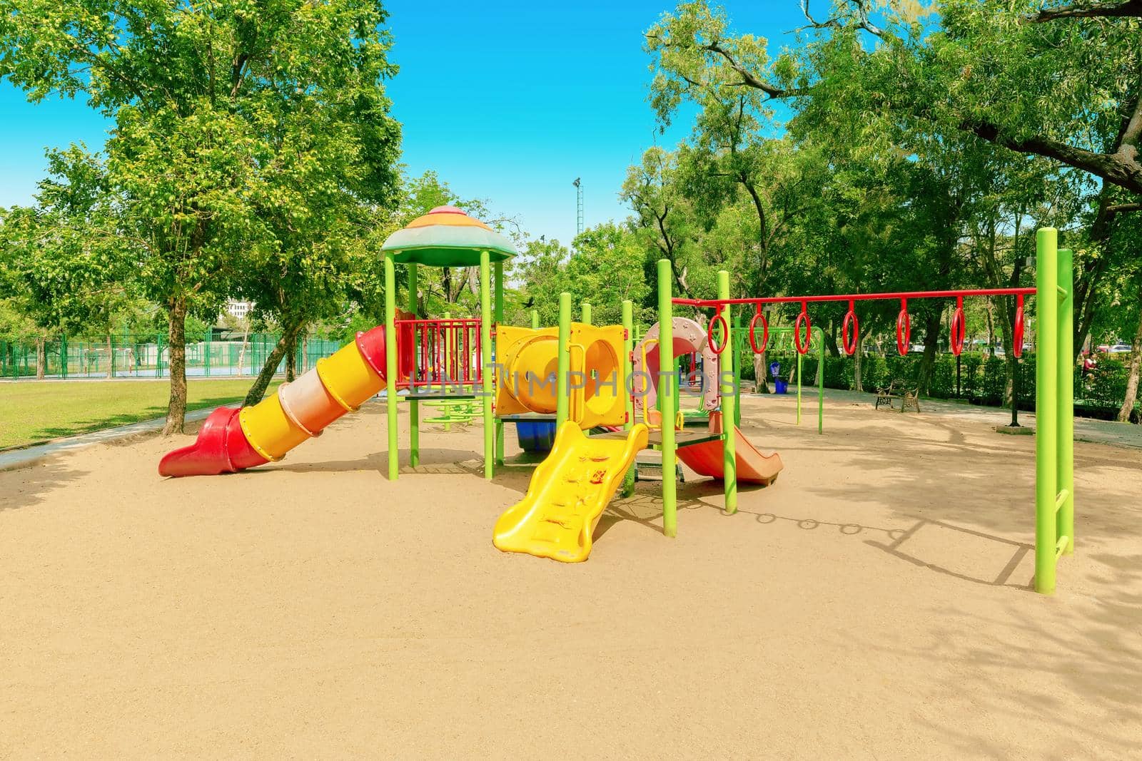 Colorful children playground activities in public park surrounded by green trees