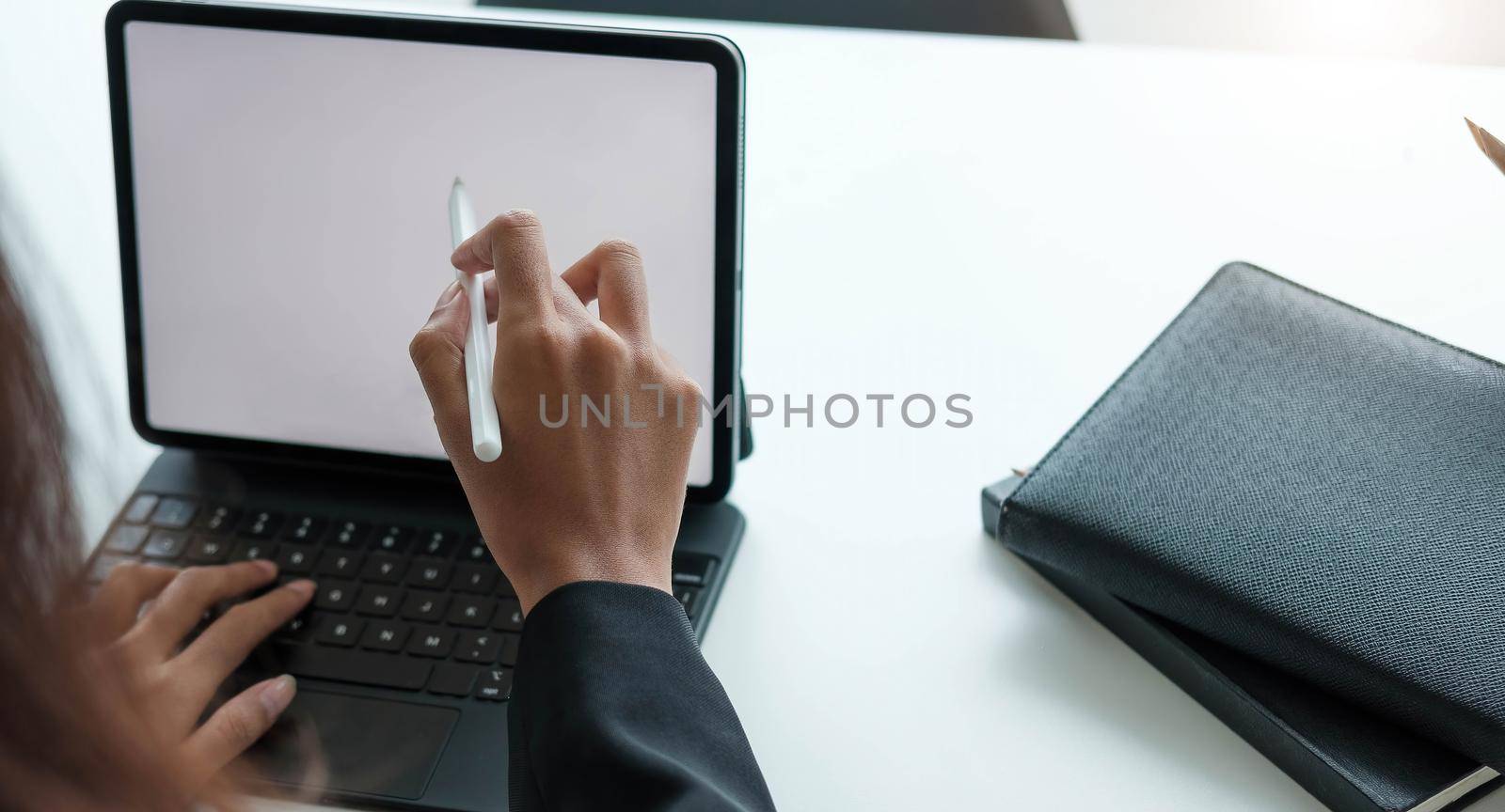 Businesswoman working with a stylus pen on a digital tablet with a laptop computer in a modern office..