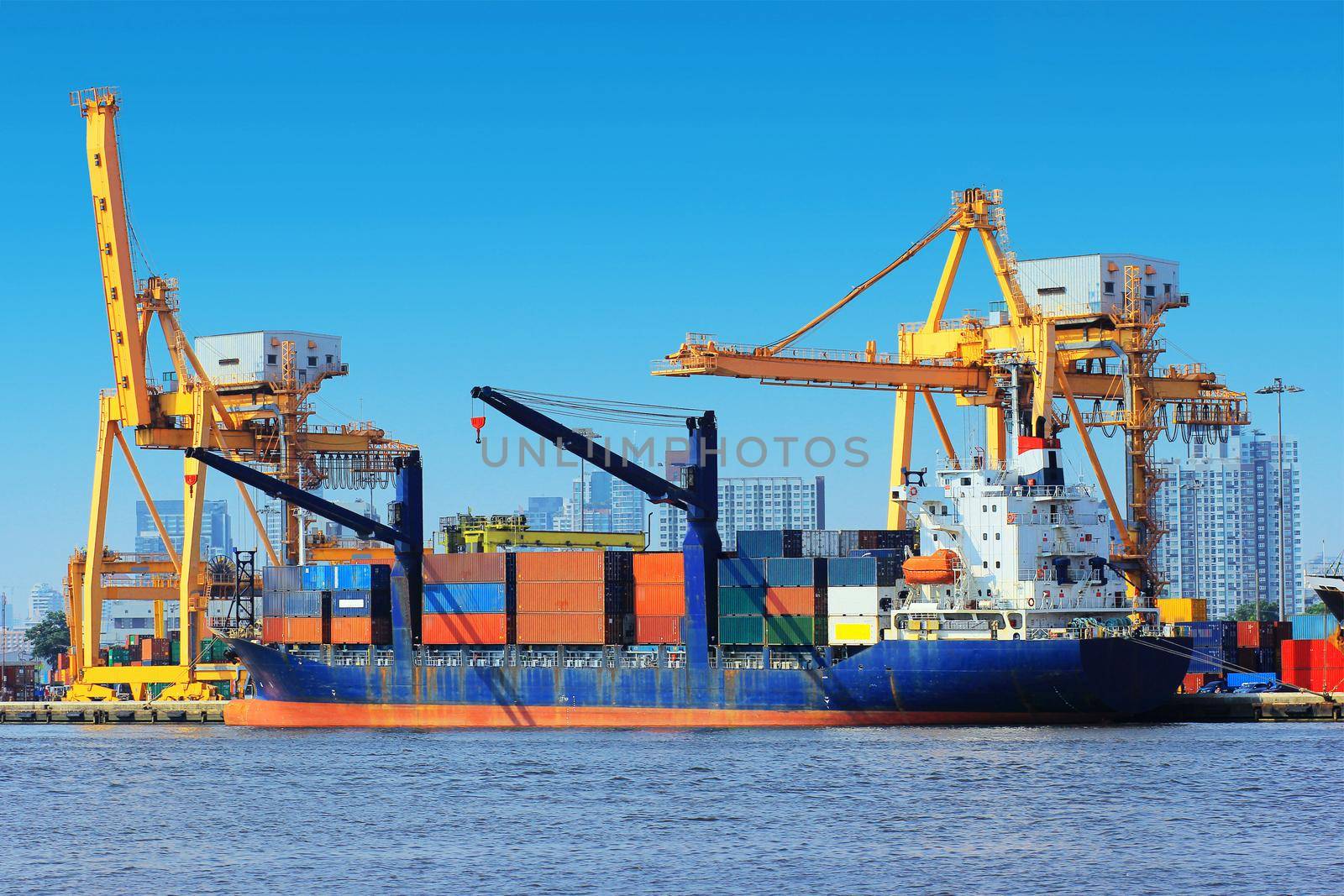 Container Cargo freight ship with working crane bridge in shipyard.