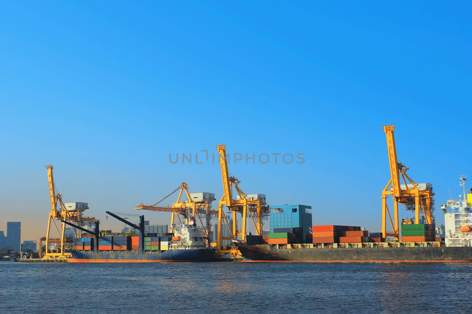 Container Cargo freight ship with working crane bridge in shipyard.