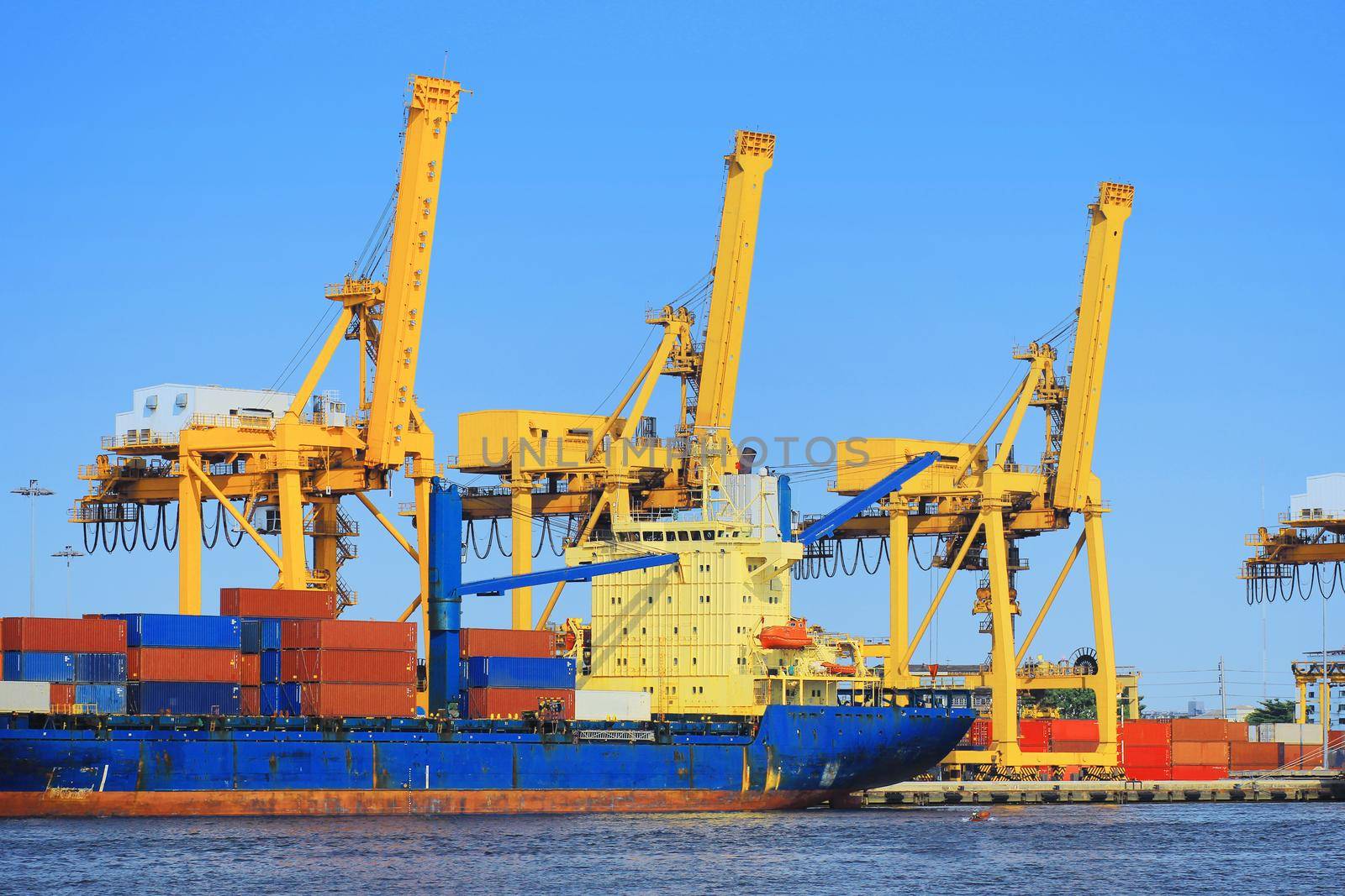 Container Cargo freight ship with working crane bridge in shipyard.