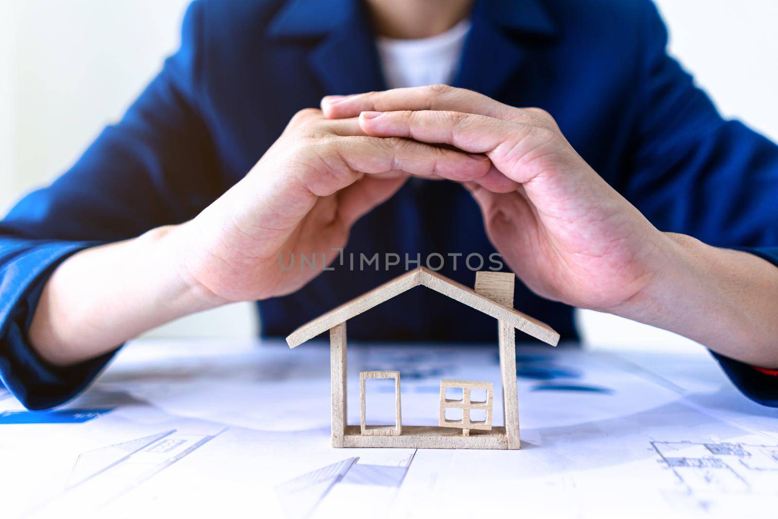 Real estate agent or Insurance agent making gestures to protect house model. Property housing insurance protection concept.