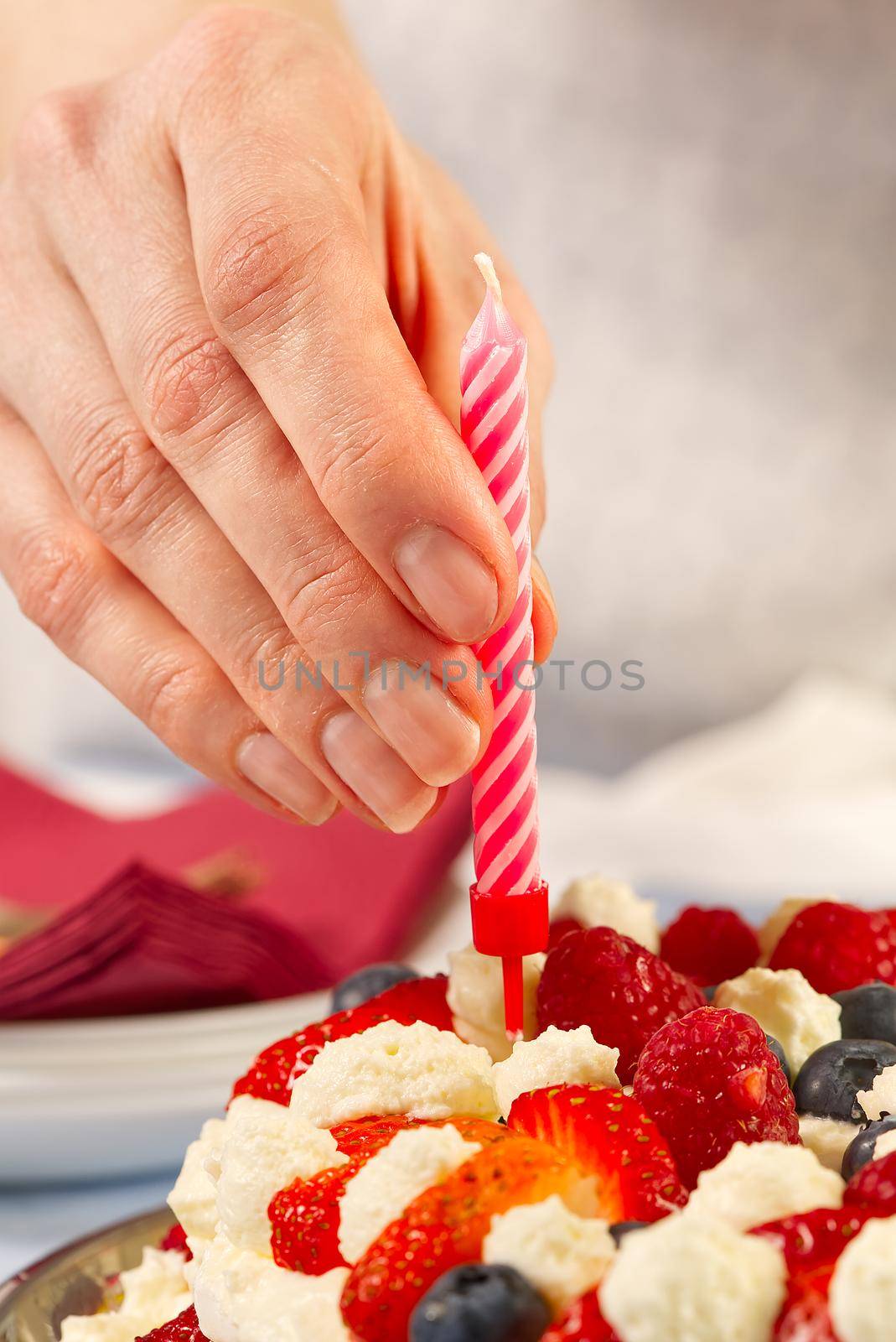 Female hand add birthday candles to homemade strawberry cake. strawberry pie and birthday candles by PhotoTime