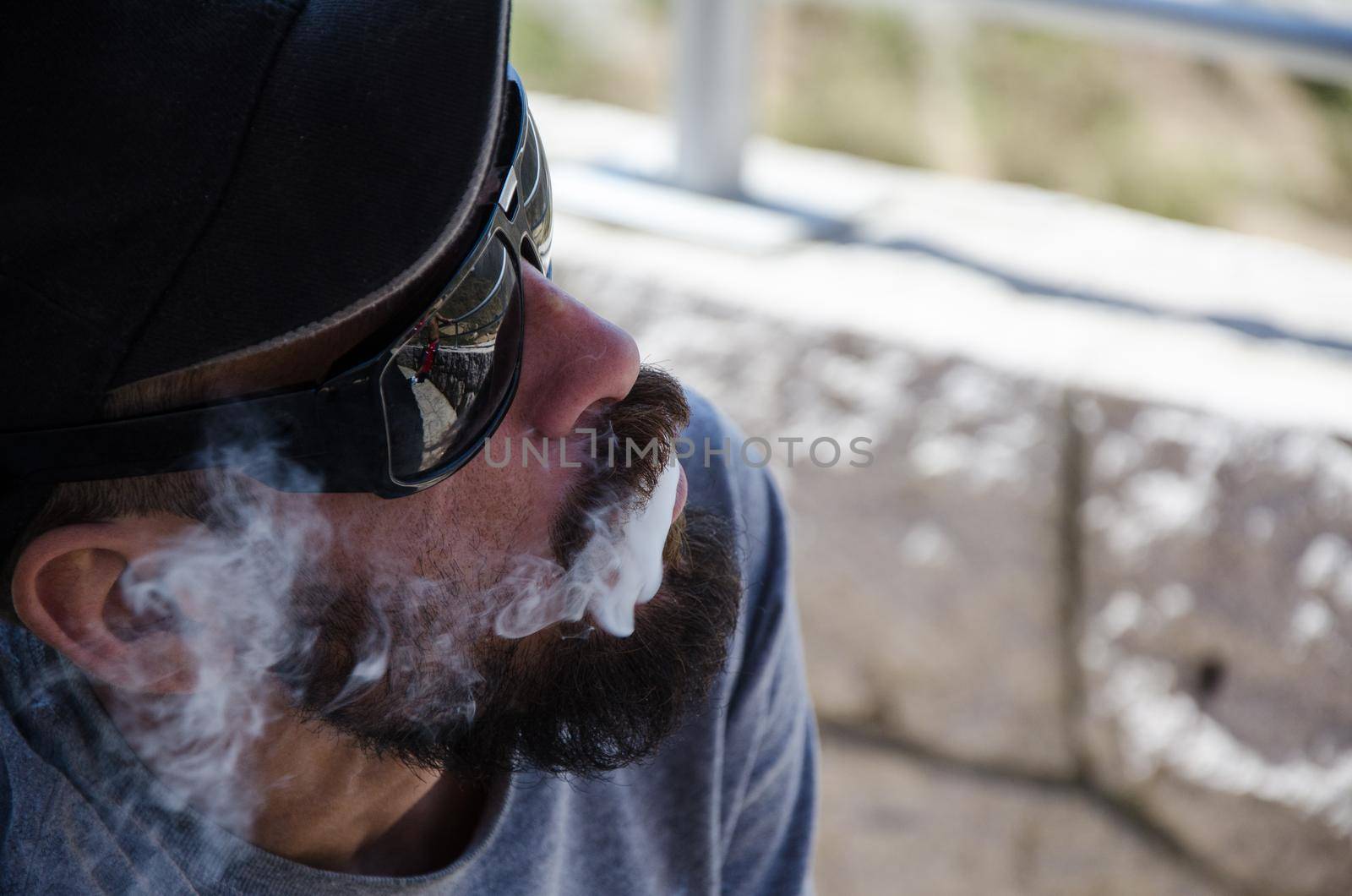 Man with sunglasses blew smoke from his mouth, low key technique