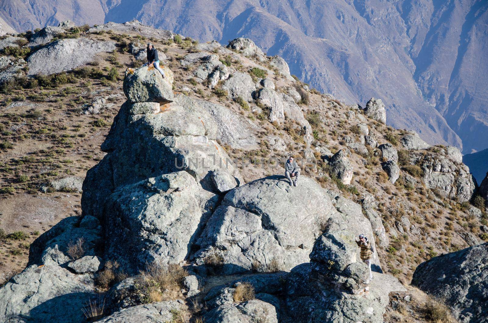 Traveling friends climbing the big rocks in Marcahuasi located east of the city of Lima - Peru