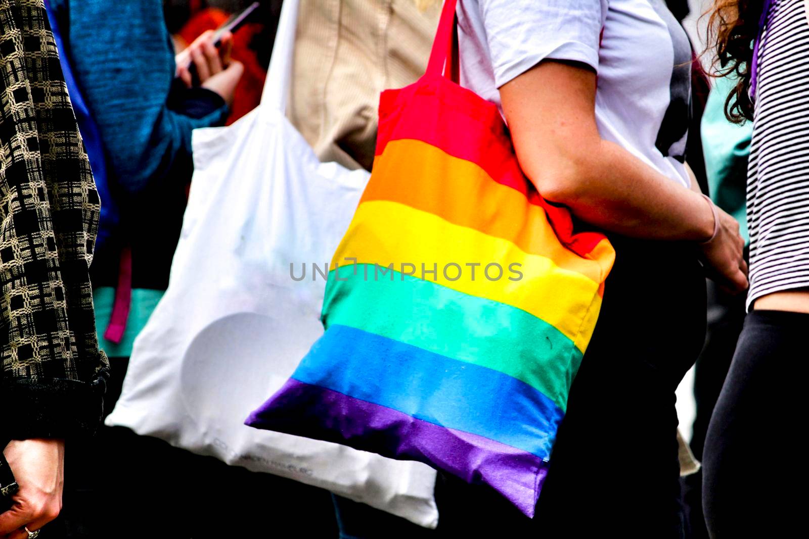 Woman carrying cloth bag in rainbow colors by soniabonet