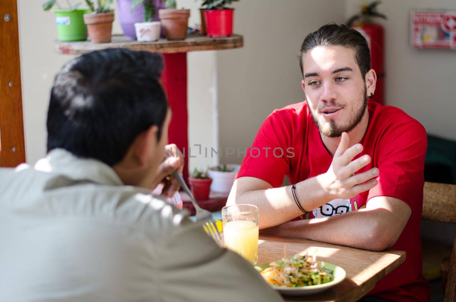 Good looking men having lunch in an outdoor restaurant, men chatting by Peruphotoart