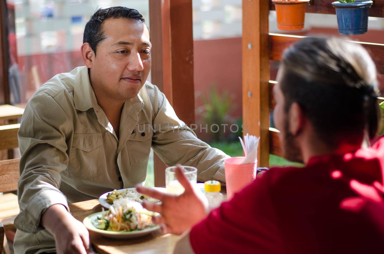 Good looking men having lunch in an outdoor restaurant, men chatting and smiling