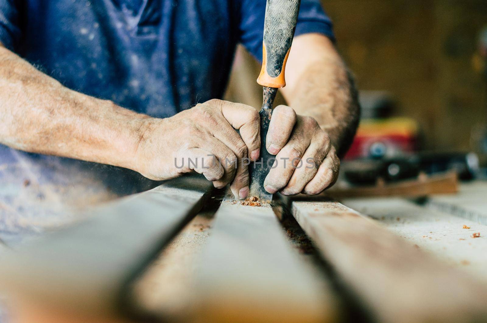 Carpenter at work, he is carving wood using a woodworking tool, hands close up, carpentry and craftsmanship concept