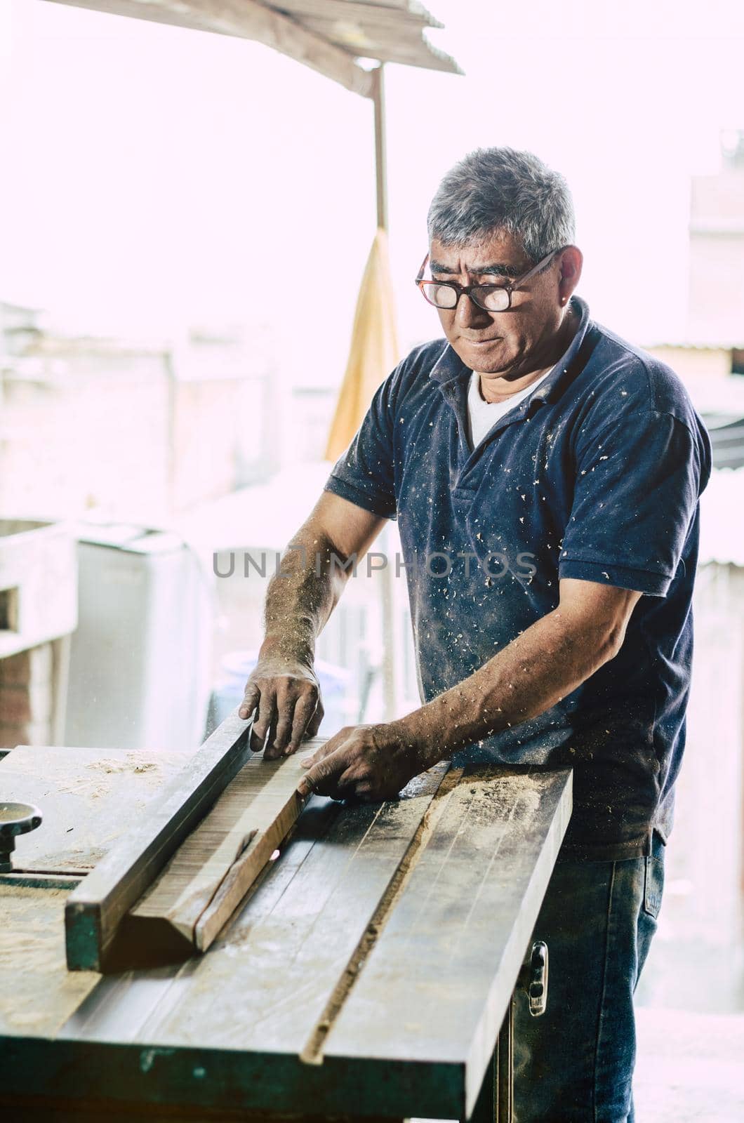 Carpenter cutting wooden board at his workshop by Peruphotoart