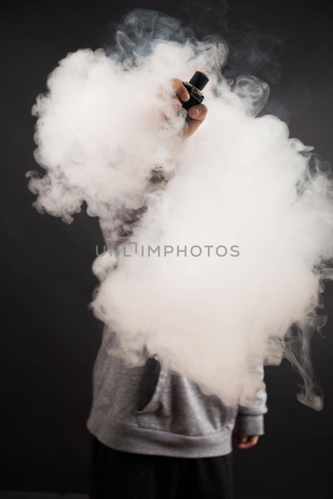 Hand of man soars on the smoke with mod in a black background. Vape concept