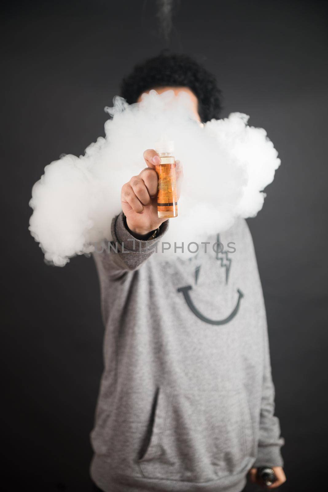 Vape concept. Smoke clouds and vape liquid bottles on dark background. Useful as background or vape advertisement or vape background.