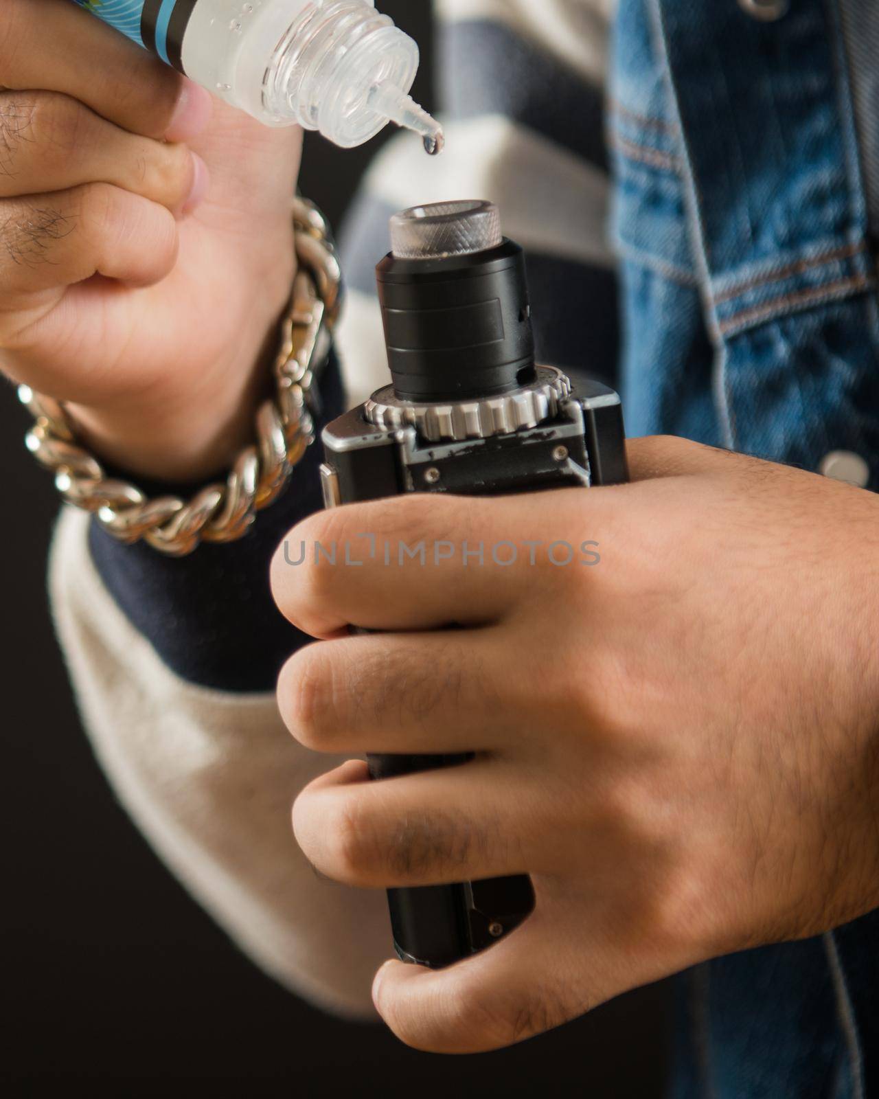 Man dripping his vape device, RDA or e-cigarette, close up, selective focus