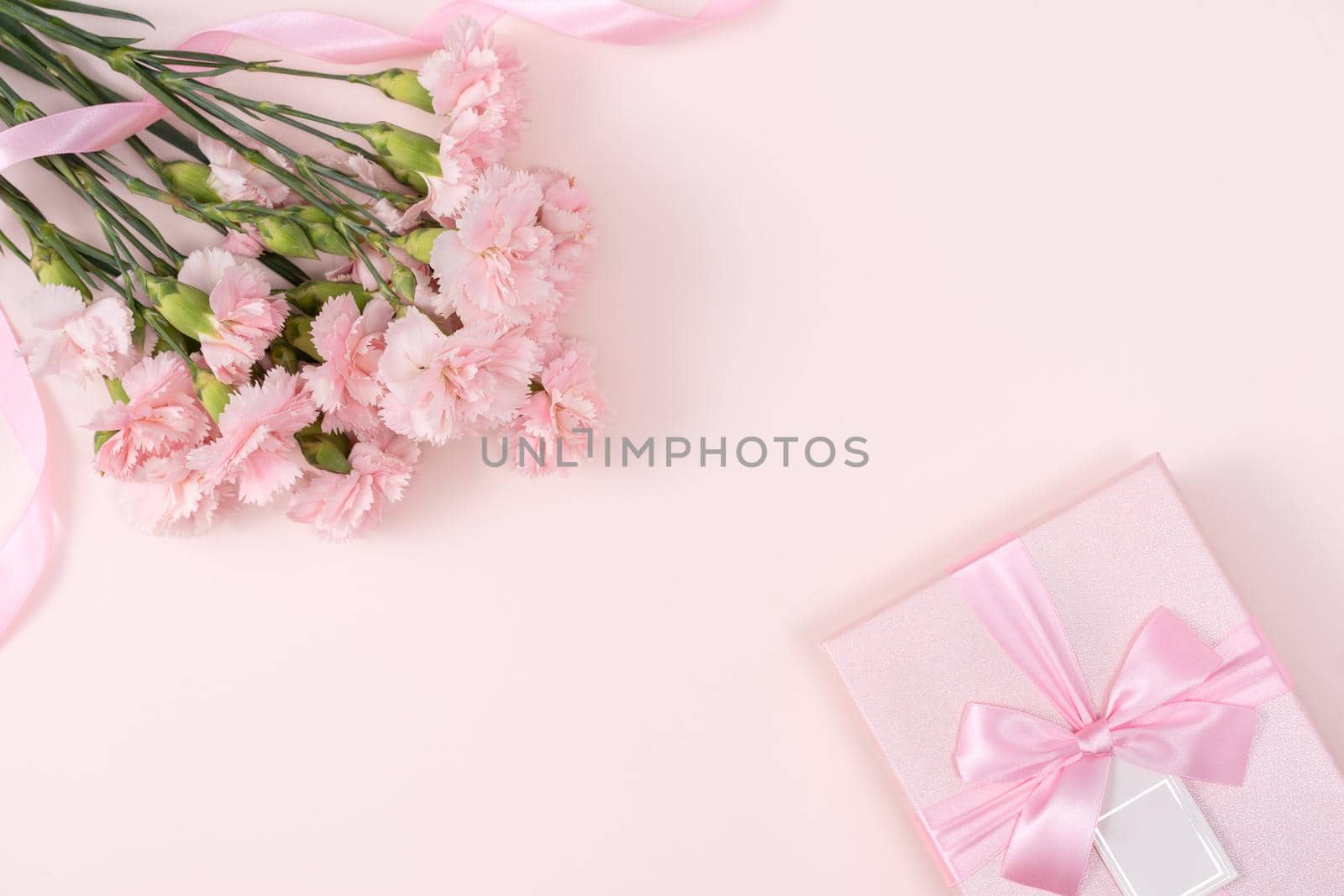 Mother's day background concept. Top view design of holiday greeting gift with carnation bouquet on bright pink table background