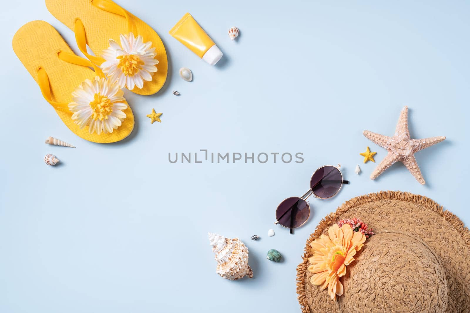 Summer beach background design concept. Top view of holiday travel with shells, hat, slipper on yellow background.