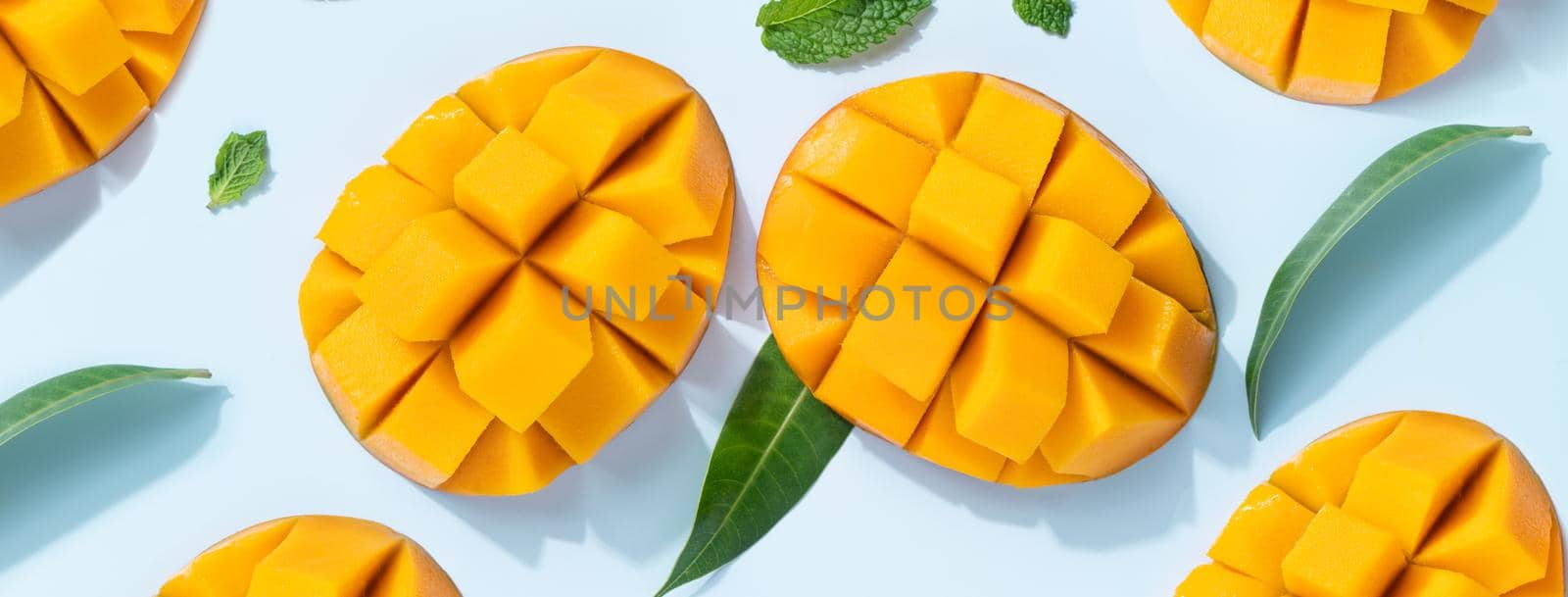 Mango design concept. Top view of diced fresh mango fruit pattern on blue table background.
