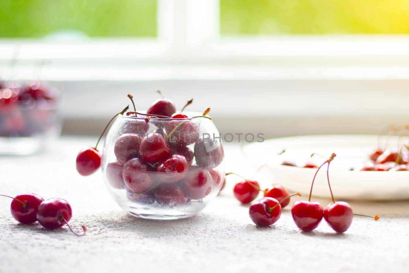 Cherry berry in a vase. Cherry berry in a transparent plate on a light background . Summer red berries. Article about berries.