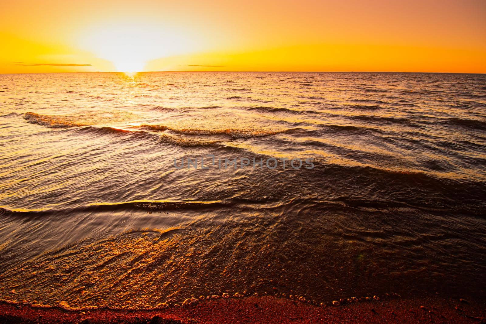 Sunset at sea. Warm sunny sunset over the sea. Sea waves. The sun sets over the horizon. The Gulf of Finland